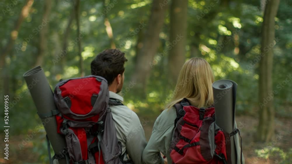 Romance and active leisure. Back view portrait of two loving man and woman with backpack walking together, follow shot Romance and active leisure. Back view portrait of two loving man and woman with backpack walking together, follow shot