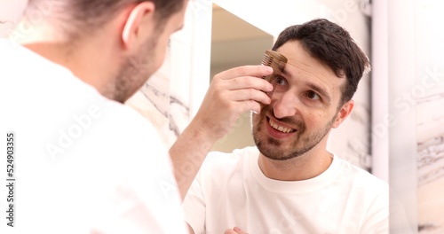 portrait of a caucasian male person combing his eyebrow.