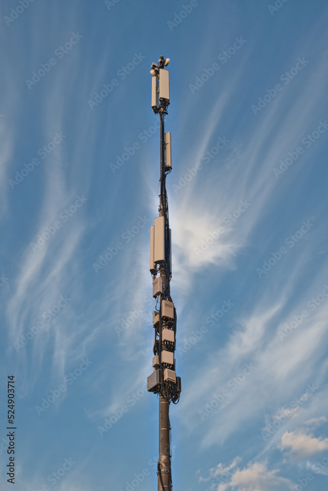 Telecommunication cell tower antenna against blue sky with clouds. Wireless communication and modern mobile internet.