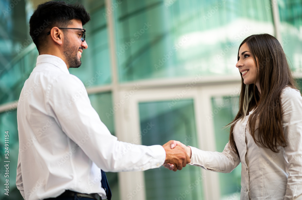 Two business partners giving a handshake outdoor in a modern setting Two business partners giving a handshake outdoor in a modern setting
