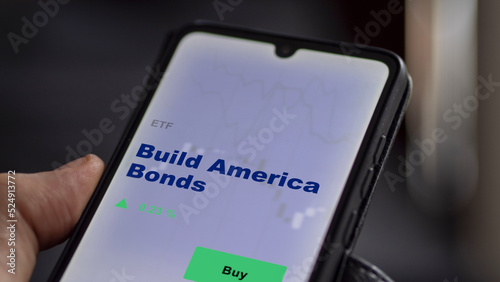 An investor's analyzing the Build America Bonds etf fund on screen. A phone shows the ETF's prices build america bonds to invest