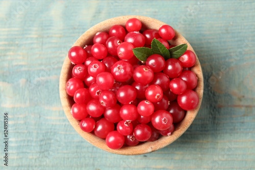 Tasty ripe cranberries on light blue wooden table, top view