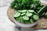 Fresh ripe cucumbers and greens on white marble table