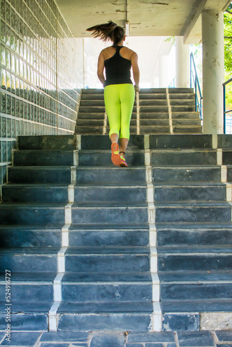 Rear view of a young woman doing sports climbing stairs.