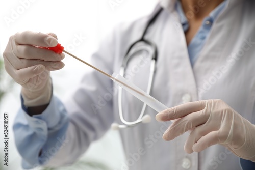 Doctor holding buccal cotton swab and tube for DNA test in clinic  closeup