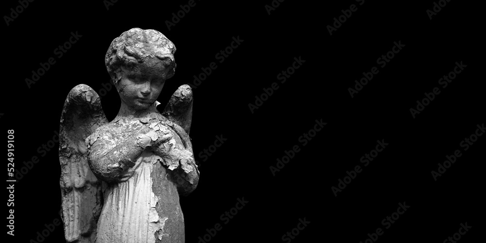 Angel. A very ancient statue on black background. Copy space. Angel. A very ancient statue on black background. Copy space.