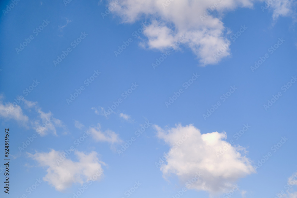 White cumulus clouds in the blue sky. Bright beautiful sky, copy space background