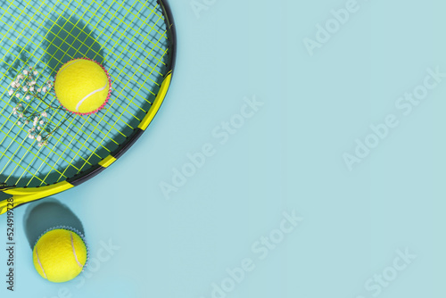 Tennis composition with yellow tennis balls and racket on a blue background of hard tennis court with copy space. Sport flat lay. The concept of outdoor game sports