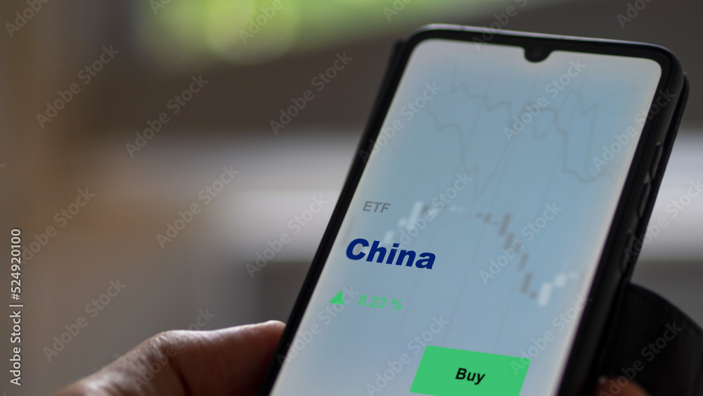 An investor's analyzing the China etf fund on screen. A phone shows the ETF's prices Chinese chinese china to invest An investor's analyzing the China etf fund on screen. A phone shows the ETF's prices Chinese chinese china to invest