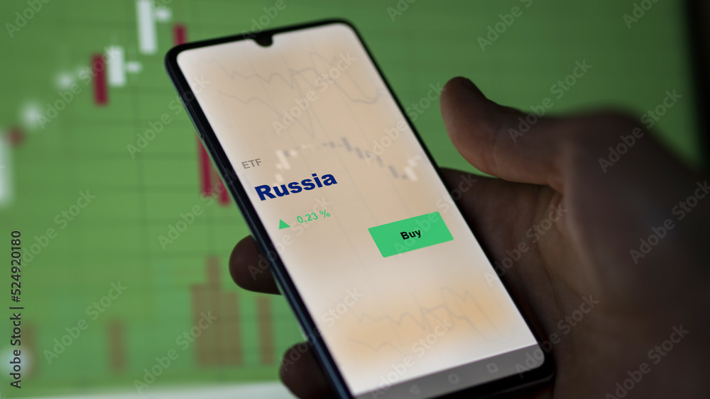 An investor's analyzing the Russia etf fund on screen. A phone shows the ETF's prices Russian to invest An investor's analyzing the Russia etf fund on screen. A phone shows the ETF's prices Russian to invest