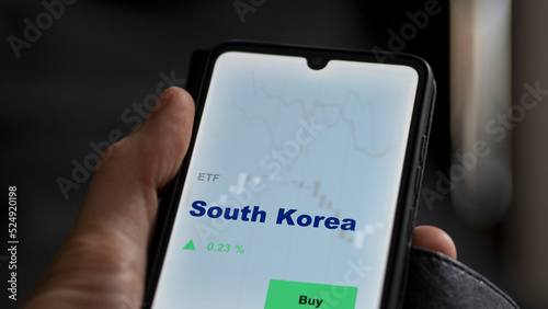 An investor's analyzing the South Korea etf fund on screen. A phone shows the ETF's prices South Korean to invest