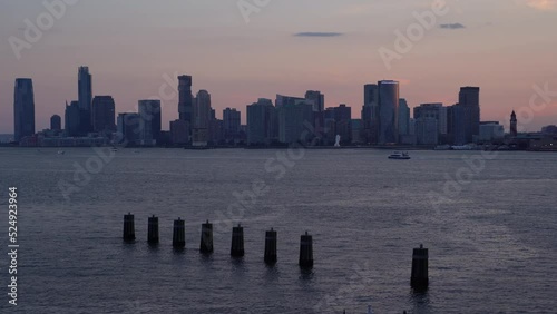 Sunset over Hudson river with ferry and ships, New Jersey sky line on background. piles sticking out of the water