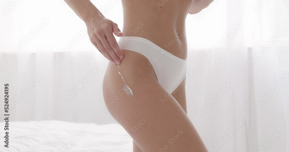 Woman smearing her thigh and buttocks with anti-cellulite moisturising cream Woman smearing her thigh and buttocks with anti-cellulite moisturising cream