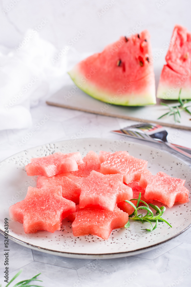 Pieces of fresh watermelon in the form of stars on a plate. Summer refreshment. Vertical view