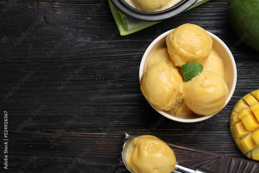 Yummy mango ice cream served on black wooden table, flat lay. Space for text Yummy mango ice cream served on black wooden table, flat lay. Space for text