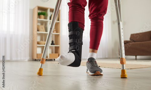 Canvas Print Man with broken leg or foot injury walking with crutches at home