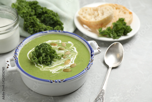 Tasty kale soup with pumpkin seeds on light grey marble table