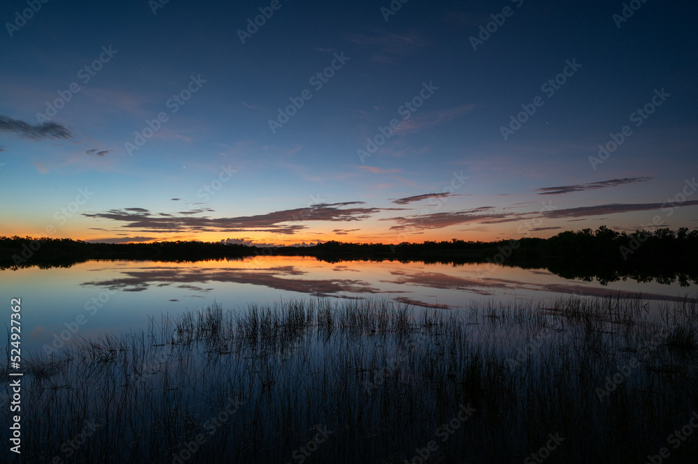 Colorful summer sunrise cloudscape over Nine Mile Pond reflected in perfectly calm water in Everglades National Park, Florida.