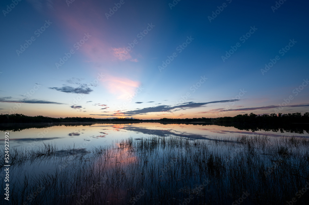 Colorful summer sunrise cloudscape over Nine Mile Pond reflected in perfectly calm water in Everglades National Park, Florida.