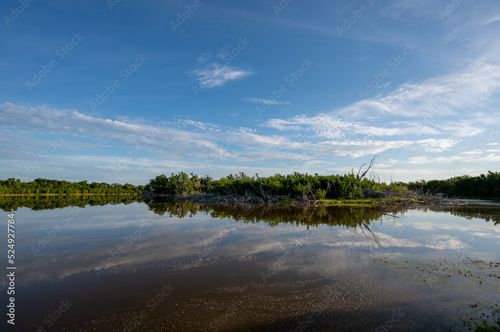 Early morning summer cloudscape over Eco Pond in Everglades National Park, Florida reflected in calm pond water.