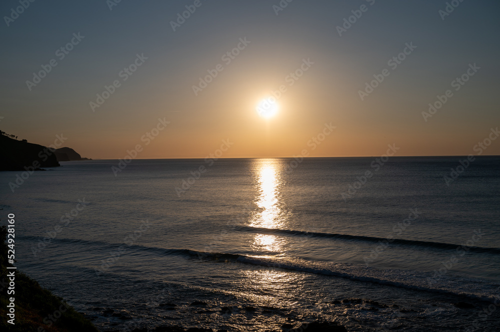 Sunset in calm waters of Atlantic ocean and clear sky