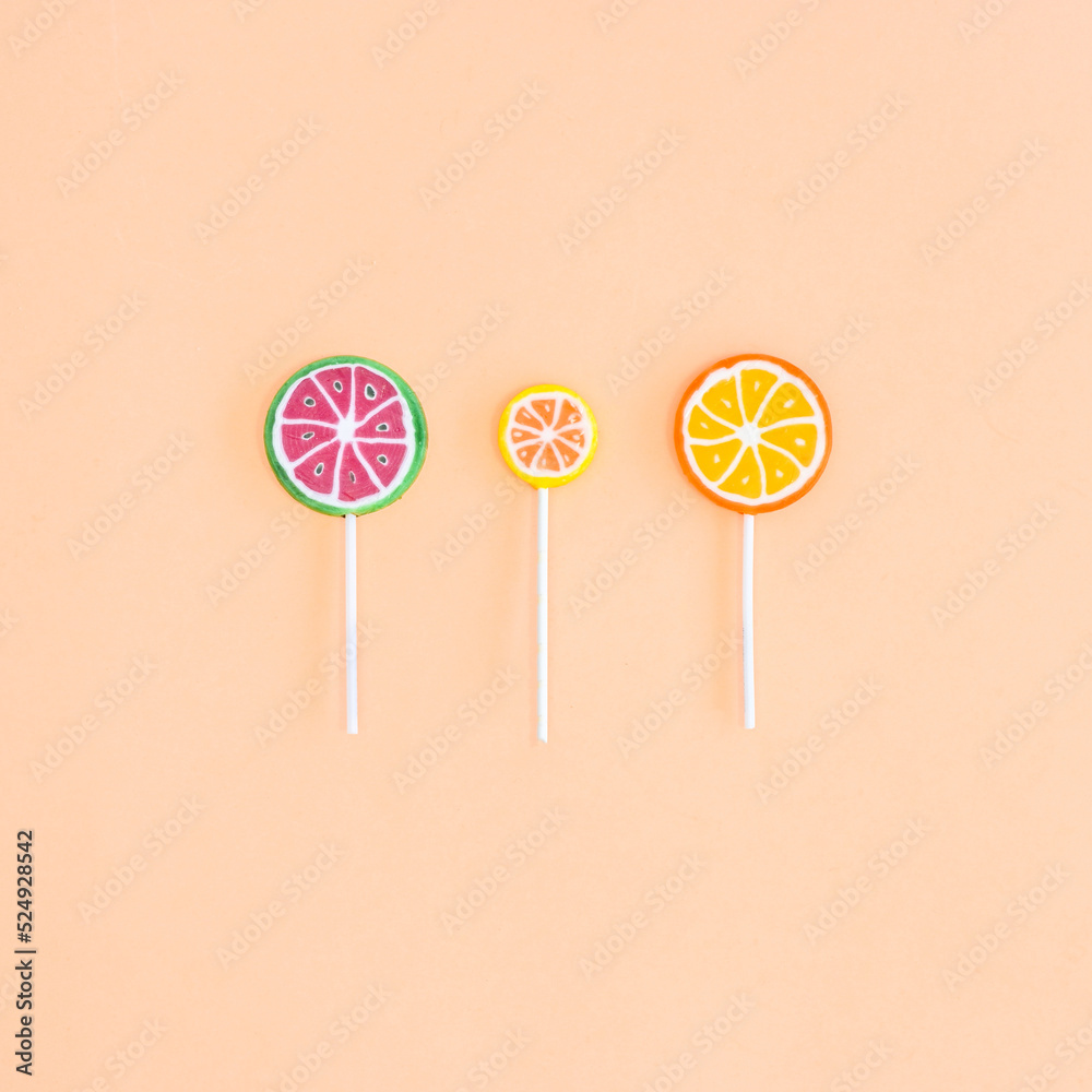Three fruity lollipops on beige background. Flat lay Three fruity lollipops on beige background. Flat lay