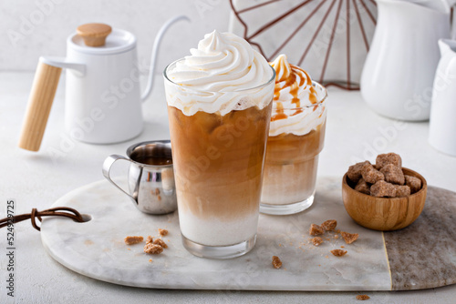 Fényképezés Iced caramel latte topped with whipped cream and caramel sauce