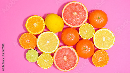 Creative summer arrangement on vibrant pink background with citrus fruits. Flat lay