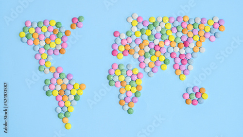 World map made with colorful candies on pastel blue bakcgorund. Flat lay. Concept Earth