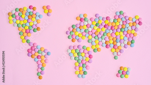 World map made with colorful candies on pastel pink bakcgorund. Flat lay. Concept Earth