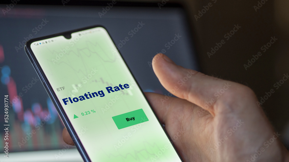 An investor's analyzing the floating Rate etf fund on screen. A phone shows the ETF's prices floating rate to invest An investor's analyzing the floating Rate etf fund on screen. A phone shows the ETF's prices floating rate to invest