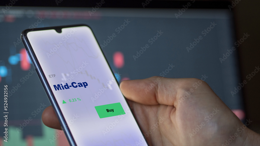 September 13th 2022, London UK. An investor's analyzing the mid-cap etf fund on screen. A phone shows the middle capitalization ETF's prices to invest September 13th 2022, London UK. An investor's analyzing the mid-cap etf fund on screen. A phone shows the middle capitalization ETF's prices to invest