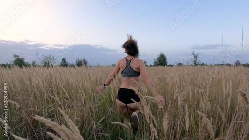 A beautiful girl in short shorts and a top runs across the field. Slow motion.