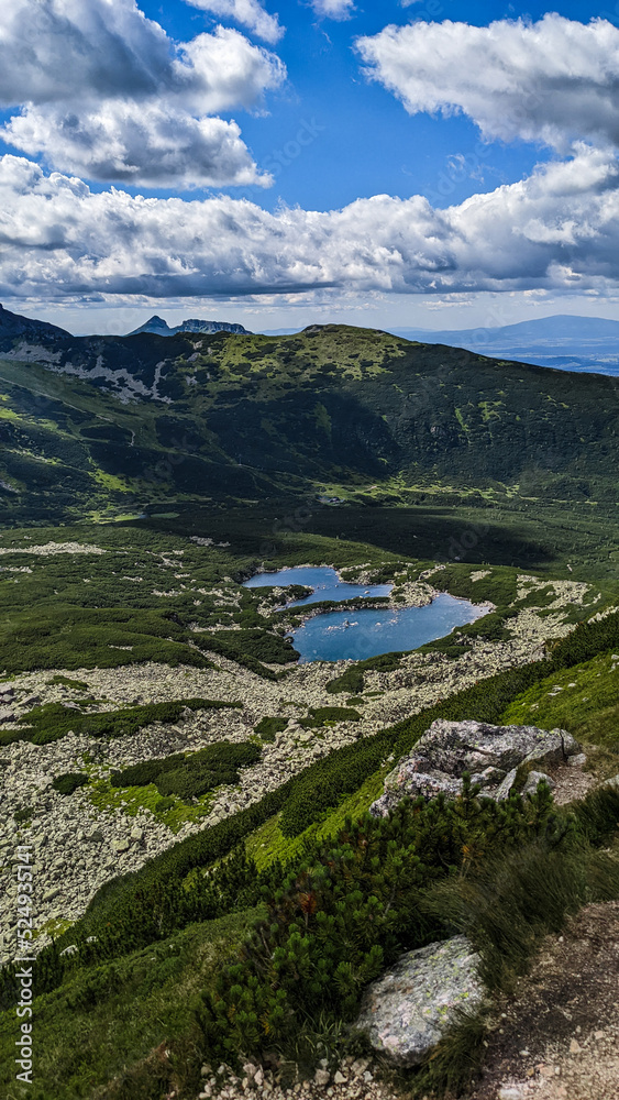 Incredible view of lakes and meadow under the mountains in the light of the sun. Beautiful landscape of lakes and mountains under the cloudy blue sky as wallpaper, poster or background. Incredible view of lakes and meadow under the mountains in the light of the sun. Beautiful landscape of lakes and mountains under the cloudy blue sky as wallpaper, poster or background.