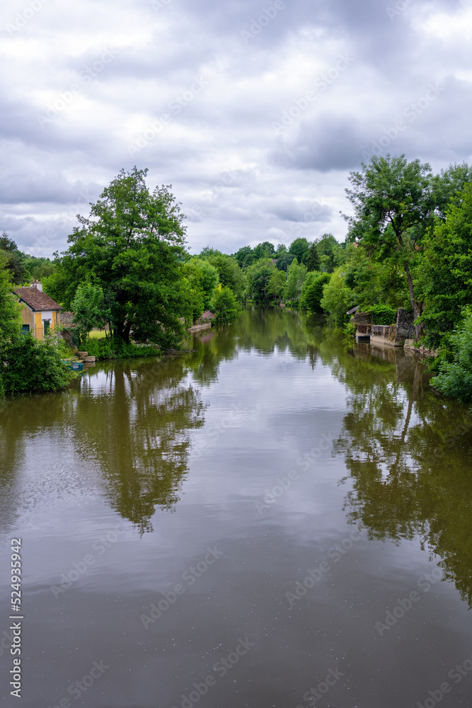 View of the river Sarthe in Fresnay-sur-Sarthe on a cloudy spring afternoon, France