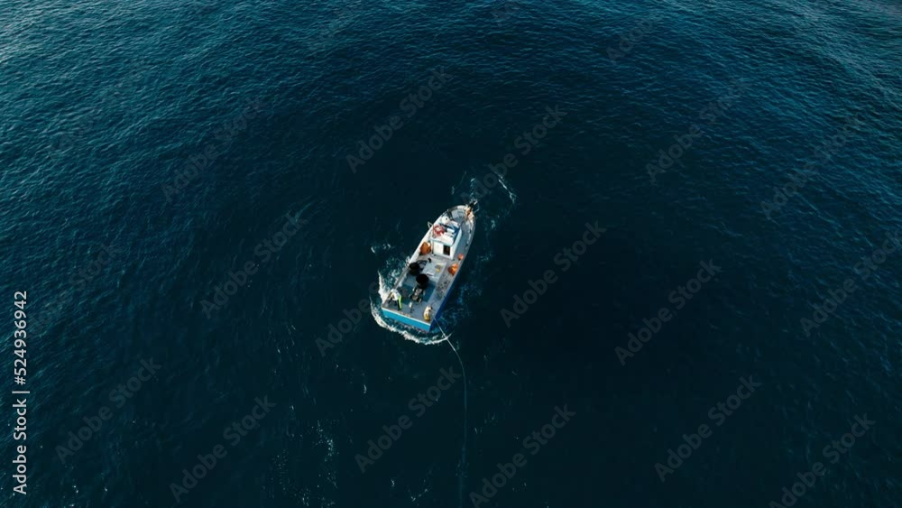 Aerial shot of fisherman boat moves around the shot trawling big net in sea underwater just before pulling it out Aerial shot of fisherman boat moves around the shot trawling big net in sea underwater just before pulling it out