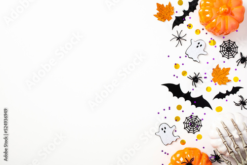 Happy Halloween flat lay composition with pumpkins, bats, ghosts, skeleton arms, spiders, webs. Top view, copy space. Halloween holiday greeting card mockup.