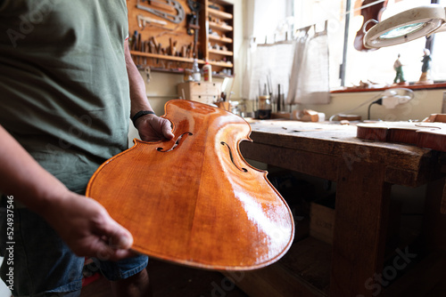 luthier attacching the front tables to the ribs of a cello in workshop