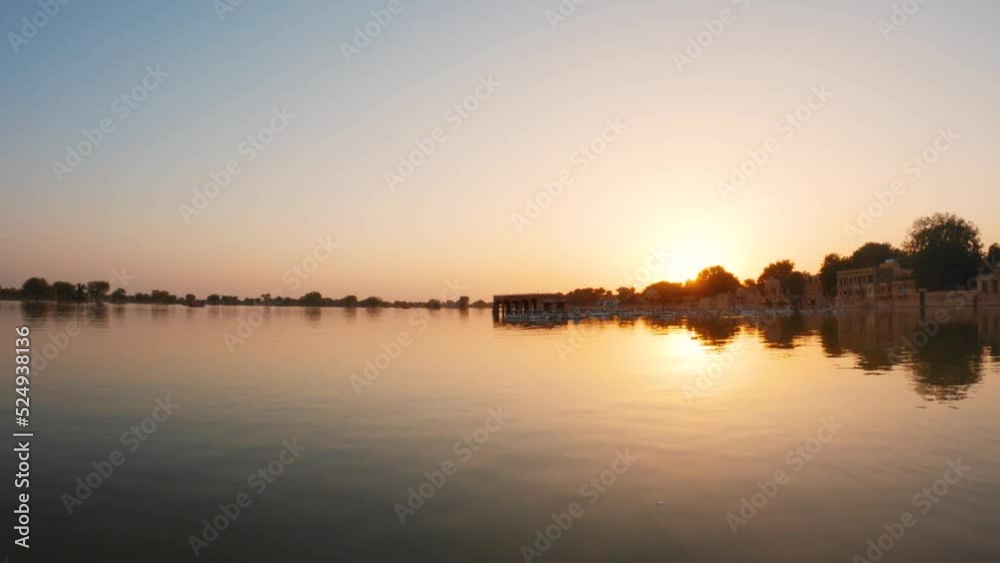 4K View of the Gadisar Lake during sunset with chhatri in the middle of the lake at Jaisalmer in Rajasthan, India. Reflection of the Chhatri pavilion in the orange water of the lake during sunset. 4K View of the Gadisar Lake during sunset with chhatri in the middle of the lake at Jaisalmer in Rajasthan, India. Reflection of the Chhatri pavilion in the orange water of the lake during sunset.