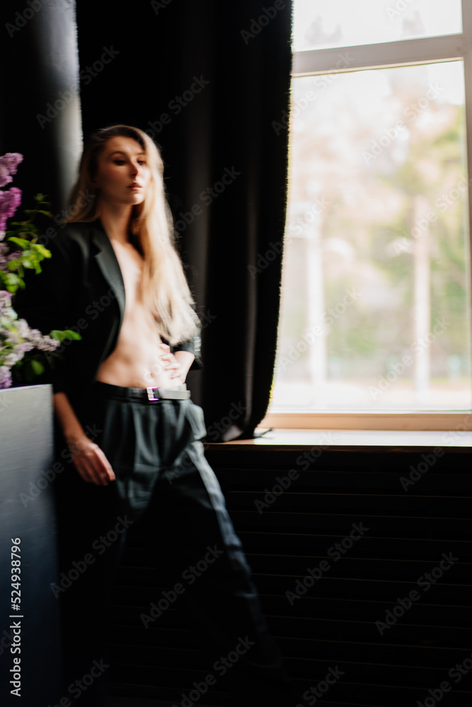 a sexy, beautiful blonde topless woman in a jacket in a dark room by the window. a sexy, beautiful blonde topless woman in a jacket in a dark room by the window.