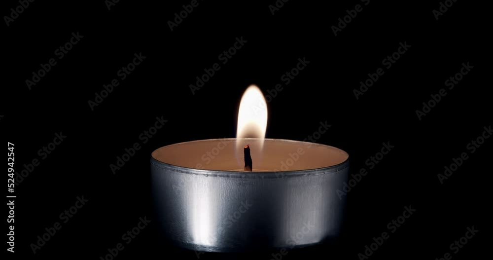 A single white candle burning.Isolated candle burning with dark background.White paraffin candle with yellow shades burns on a black background.Background or illustration of remembrance or celebration A single white candle burning.Isolated candle burning with dark background.White paraffin candle with yellow shades burns on a black background.Background or illustration of remembrance or celebration