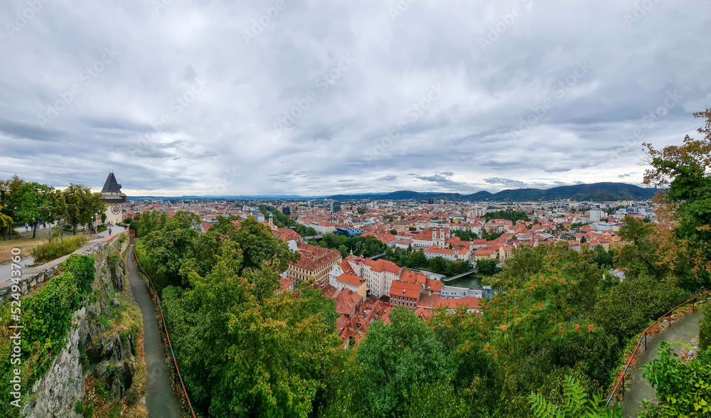 Cityscape of old town of Graz and the Clock Tower (Grazer Uhrturm), famous tourist attraction in Graz, Steiermark, Austria, in cloudy summer day.