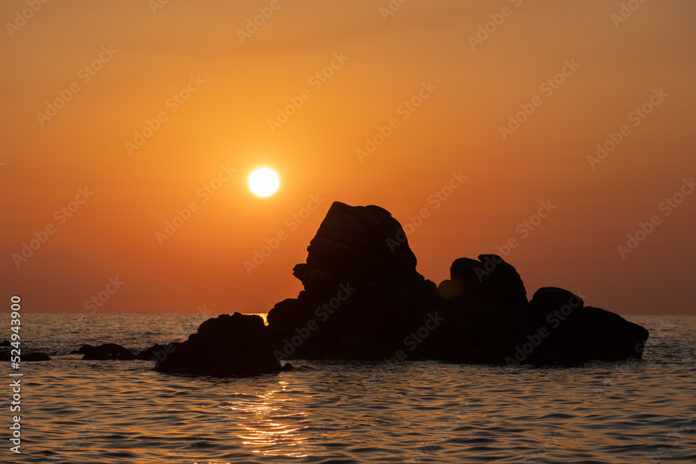 Beautiful view of orange sunset with rocks in Calabria, Mediterranean Sea, Italy. Tropical colorful sunrise landscape. Seascape