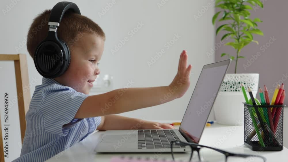 little boy child kid in headphones saying hallo laptop webcam, speak video call. children using technology in learning, communicating, studying. preschooler pupil internet distant class