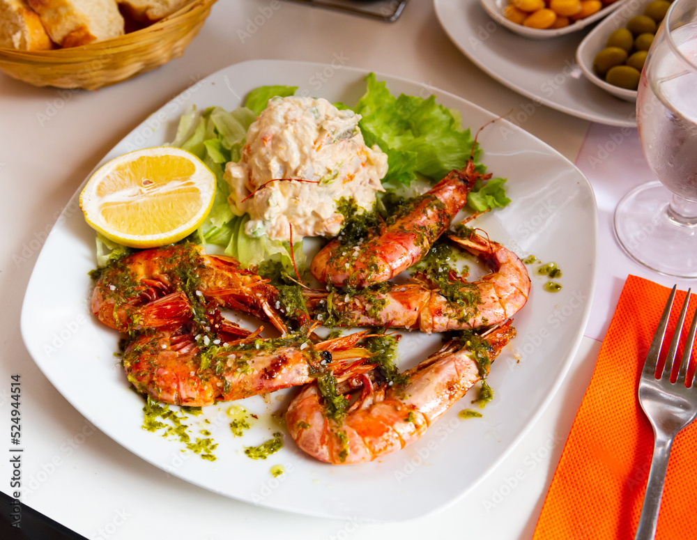Roasted shrimps served with sauce, cheese salad and lemon