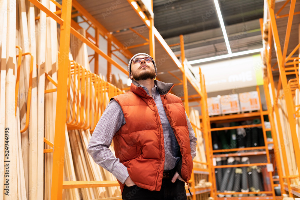 a man in a lumber store examines the assortment while looking at the racks with goods