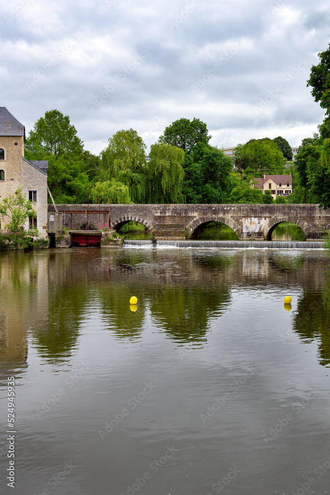 View of the Sillé bridge and the Creusot grain water mill over the river Sarthe on a cloudy spring day, Fresnay-sur-Sarthe, France