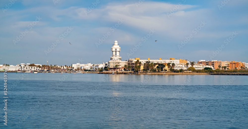 View of the tourist town and lighthouse of Isla Cristina from Isla del Moral with the  Carreras River near the mouth of the sea, Huelva, Andalusia, Spain