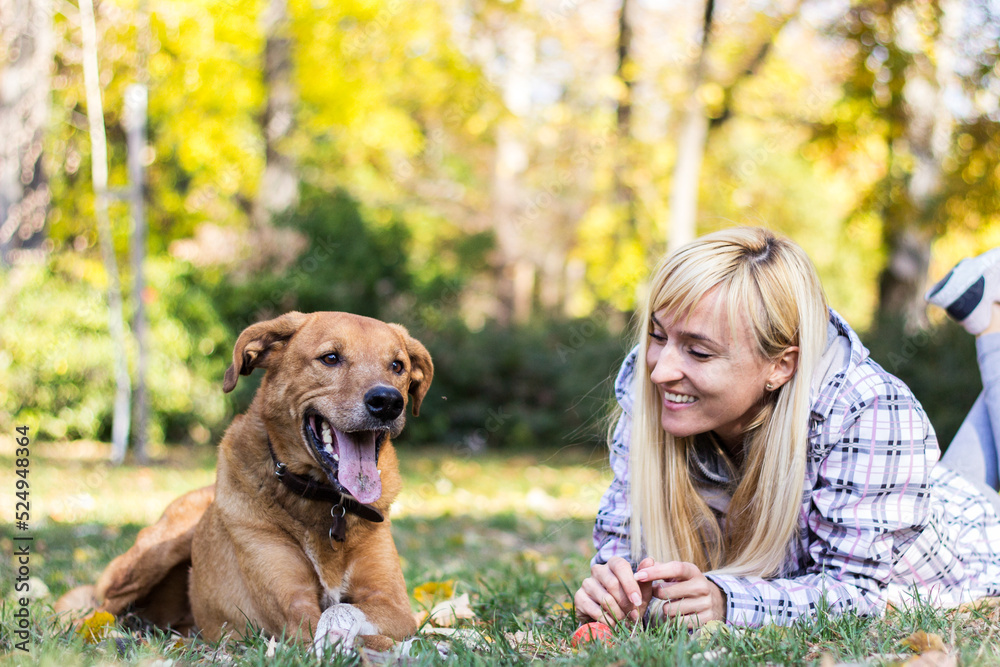 Happy young adult woman enjoys time at a park with her dog