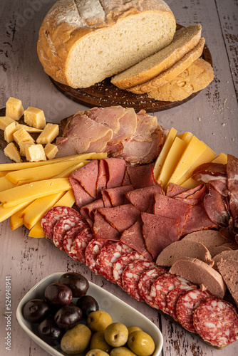 Picada, plato típico de embutidos, quesos y aceitunas, aperitivo argentino y español, sobre una tabla de madera. photo